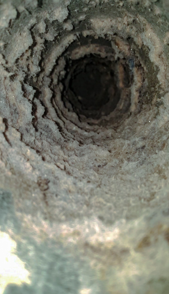 Untitled design (3) Close-up view inside a rusted, corroded metal pipe—its rough, layered buildup along the interior walls contrasts sharply with the pristine results achieved by the best carpet cleaning. A dark, shadowy center adds depth to the scene.